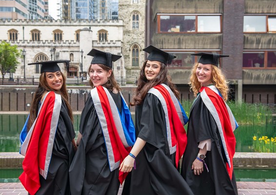 Four females at graduation at the water front at the Barbican Centre