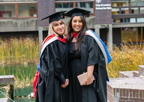 Two smiling female graduations outside at the Barbican centre